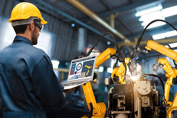 Man holding laptop in connected manufacturing plant