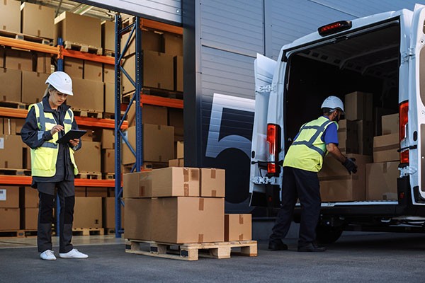 Two people loading boxes into a delivery van