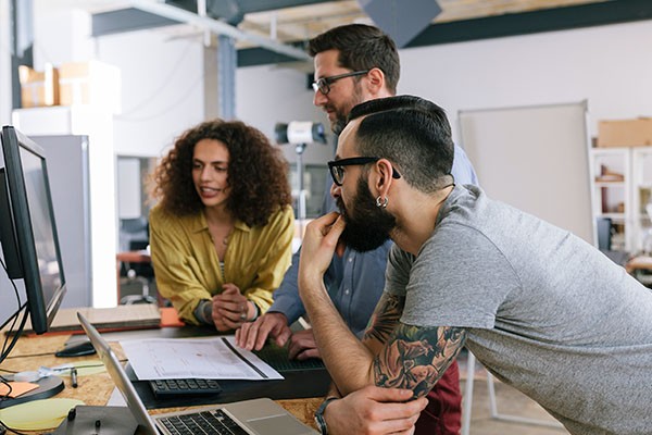 Group of people huddled around a computer working