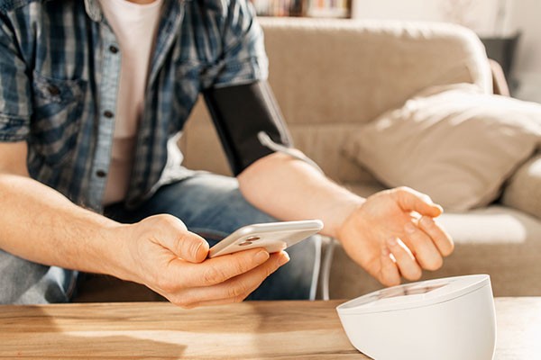 Man taking blood pressure reading from digital device at home