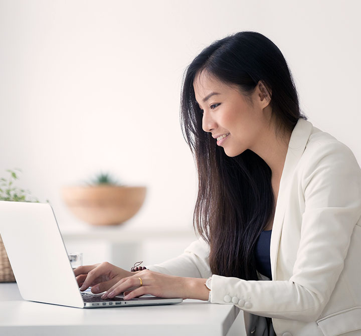 A woman is working on a laptop computer equipped with Office@Hand for improved communications with remote offices.