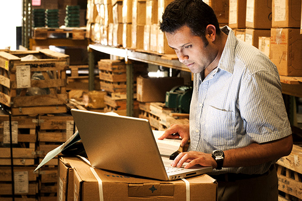 A man on a laptop in a warehouse